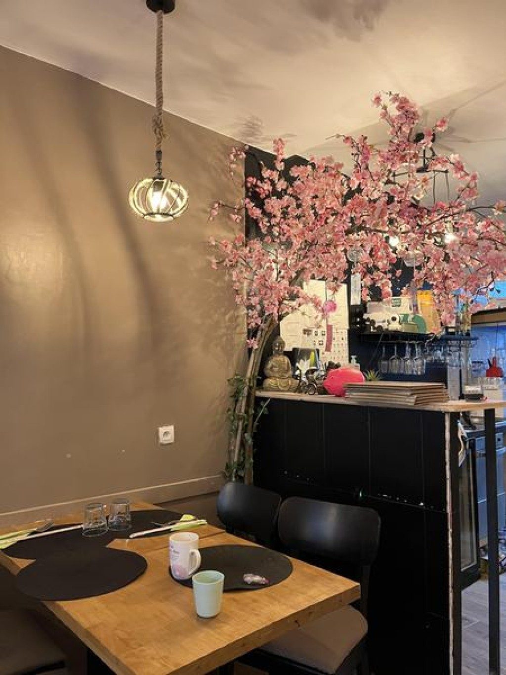 La salle, ses tables en bois clair et un cerisier en fleurs décoratif